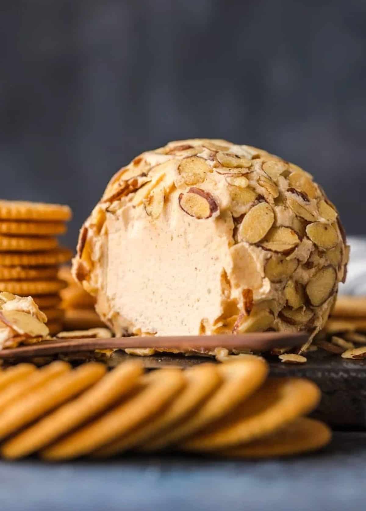 Almond cheese ball recipe with crackers on a cutting board.