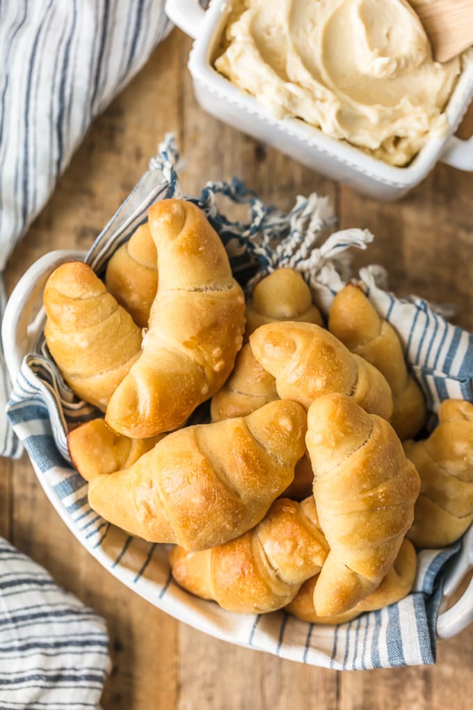 A basket of crescent rolls next to a container of honey butter