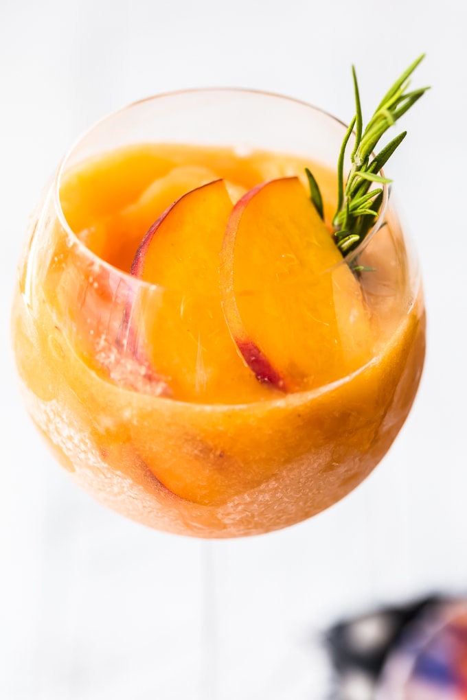 This Peach Frosé Recipe is a cocktail you definitely need for this hot Summer heat! All you need is frozen peaches, some Rosé wine, and a little honey. Frozen Rose is such a quick and easy fun cold drink to throw together for parties, friends and family, or just a quiet afternoon at home. We will show you how to make Frose and spice things up with this Peach Frose Recipe. So delicious, easy, fresh, and fun! Up close shot of peach frose