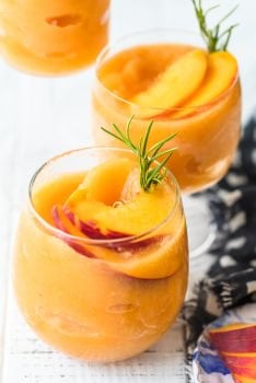 This Peach Frosé Recipe is a cocktail you definitely need for this hot Summer heat! All you need is frozen peaches, some Rosé wine, and a little honey. Frozen Rose is such a quick and easy fun cold drink to throw together for parties, friends and family, or just a quiet afternoon at home. We will show you how to make Frose and spice things up with this Peach Frose Recipe. So delicious, easy, fresh, and fun!