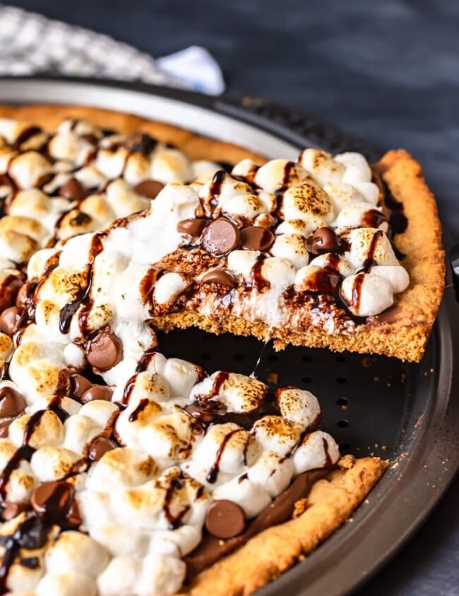 S'mores Dessert Pizza is a sweet, chocolaty dessert made just like a pizza! It's got the classic s'mores flavor of melted chocolate, graham crackers, and fluffy marshmallows, all melted together into the most amazing s'mores pizza. This easy dessert pizza recipe is fun to make and even more fun to eat!