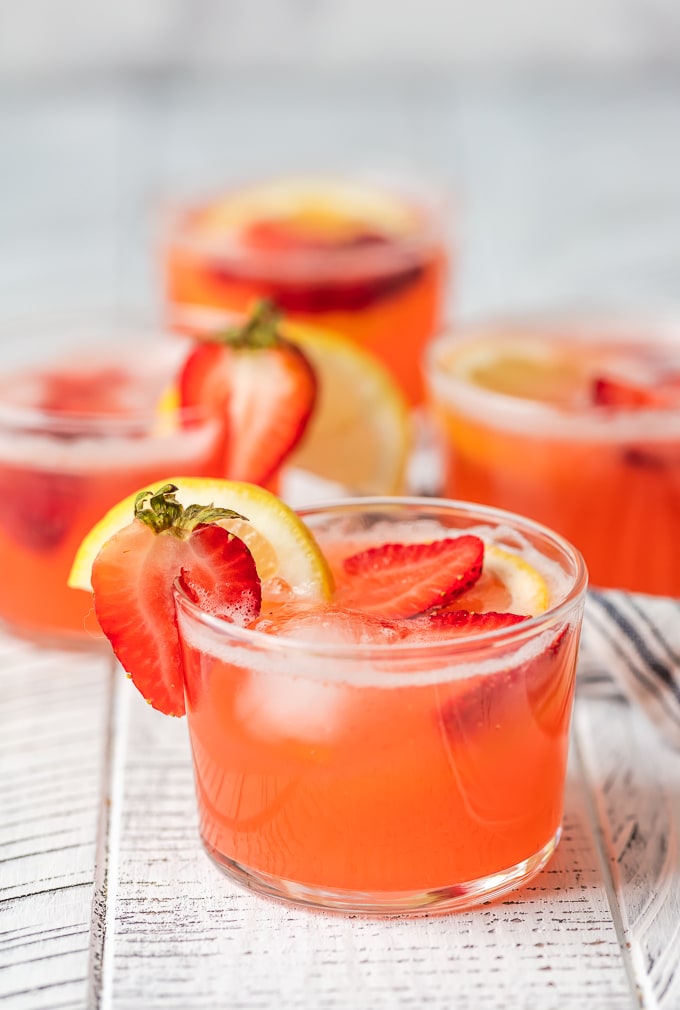 Strawberry Lemonade Party Punch is the best summer punch recipe! This refreshing drink is made with Everclear for the perfect party punch recipe. Glasses of strawberry lemonade punch garnished with fresh slices of lemon and strawberries