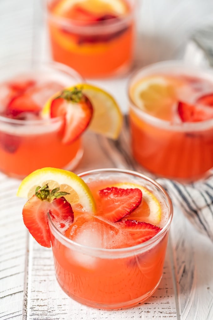 Strawberry Lemonade Party Punch is the best summer punch recipe! This refreshing drink is made with Everclear for the perfect party punch recipe. 4 short glasses filled with strawberry lemonade party punch