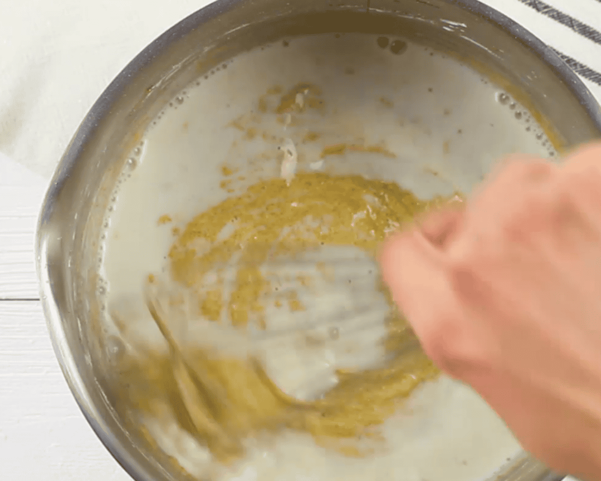 Adding the hot milk to the custard mixture.