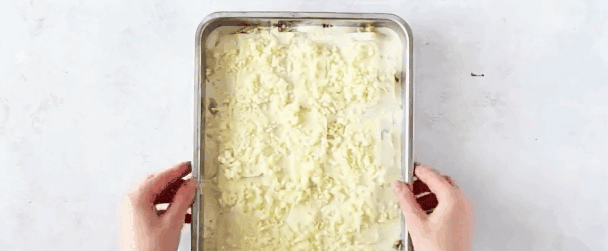 Cheese topped lasagna in a baking pan.