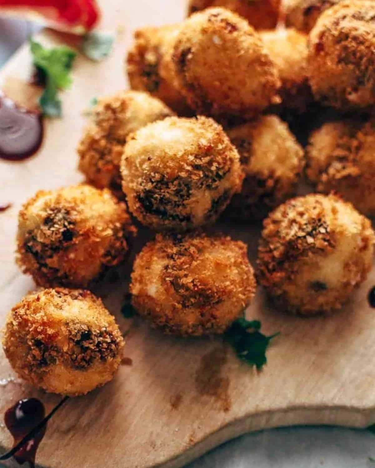 Fried Goat Cheese Balls are the perfect New Year's Eve appetizer! These goat cheese poppers are stuffed with dried cherries and pecans and then deep fried into a crispy little snack. It's definitely my favorite goat cheese appetizer! A plate of fried goat cheese balls with pecans and dried cherries.