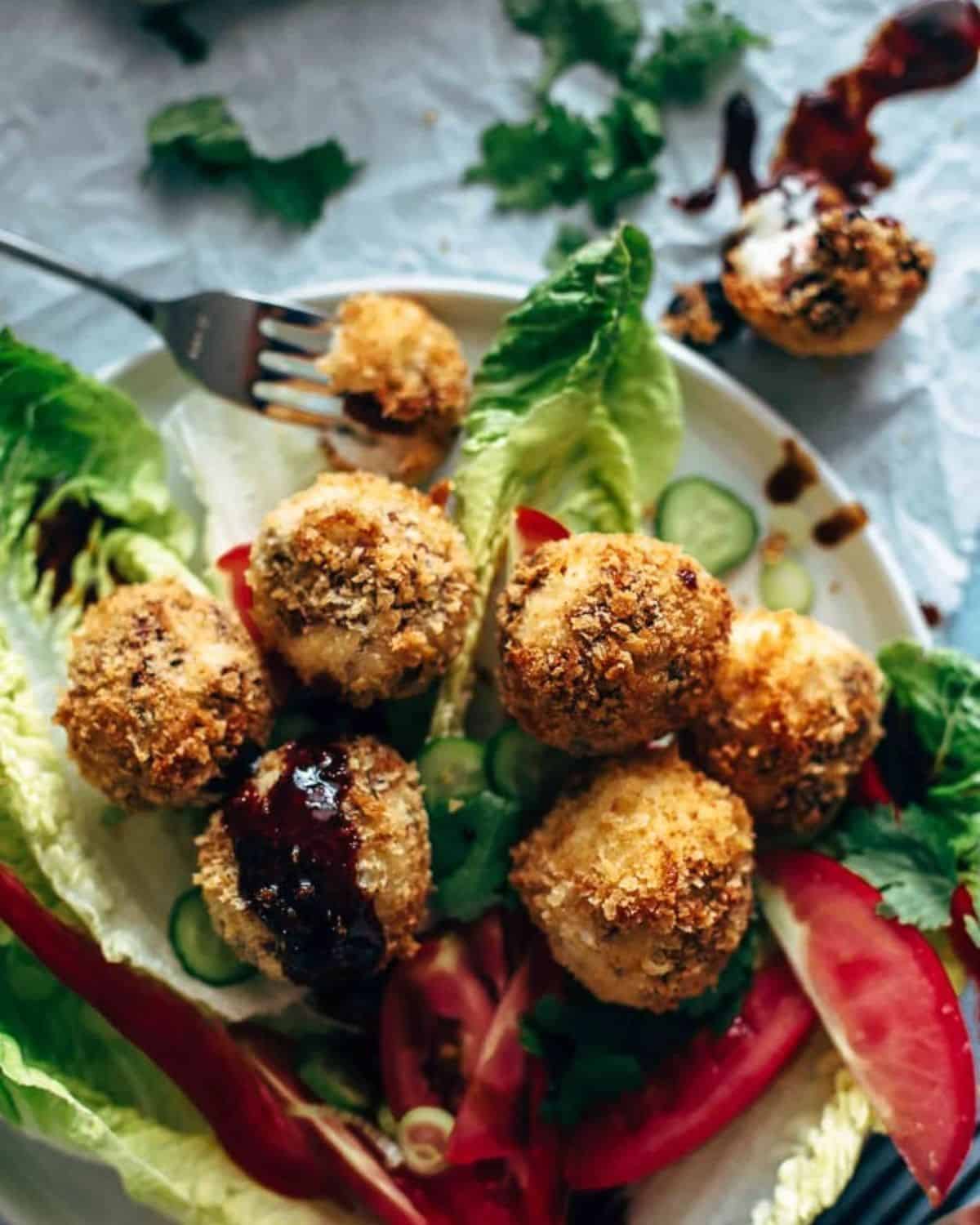 Fried Goat Cheese Balls are the perfect New Year's Eve appetizer! These goat cheese poppers are stuffed with dried cherries and pecans and then deep fried into a crispy little snack. It's definitely my favorite goat cheese appetizer! Fried goat cheese balls on a plate with a fork lifting a piece.