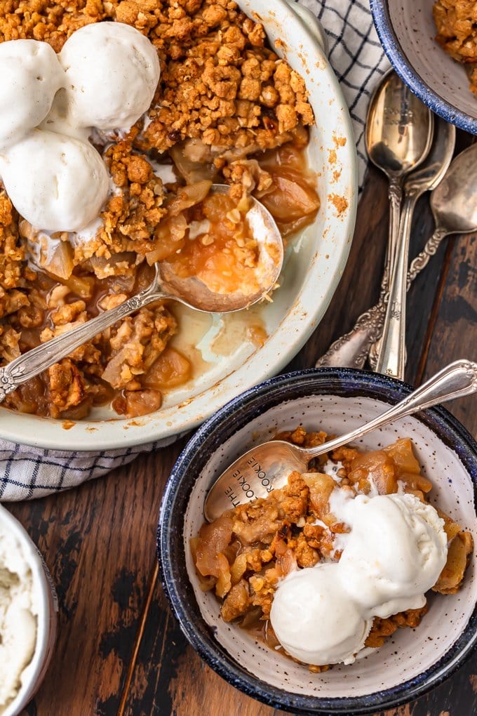 Fresh apple crisp in a baking dish, next to a bowl of apple crisp topped with ice cream