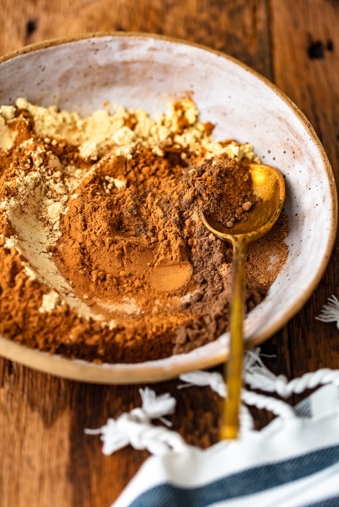 A bowl of mixed spices with a gold spoon