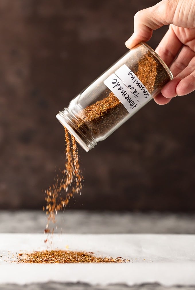 Pouring taco seasoning out of a glass jar