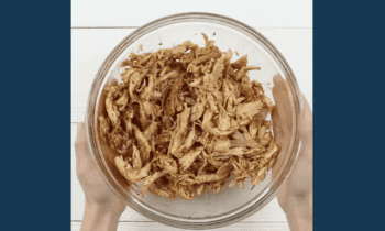 marinated shredded cooked chicken in a glass bowl.