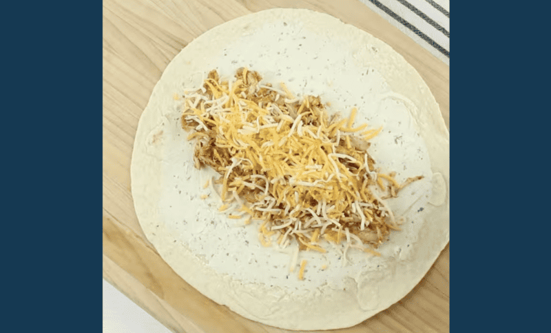 a flour tortilla topped with boursin cheese, shredded chicken, and monterey jack cheese.