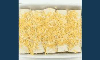 enchiladas in a baking pan topped with cheese.
