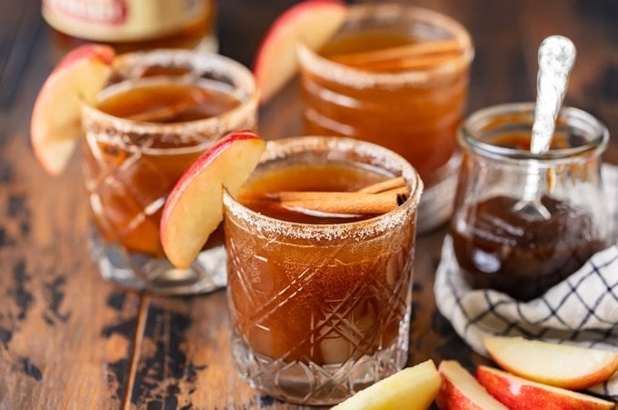 3 apple old fashioneds in glasses garnished with apple and cinnamon