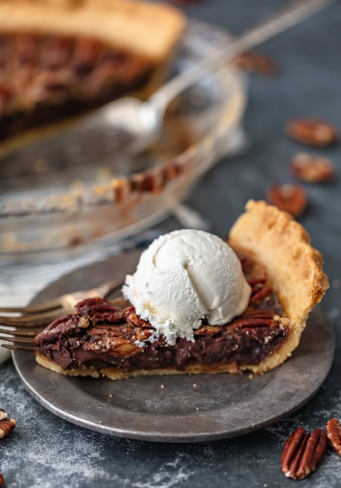 A slice of chocolate pecan pie topped with a scoop of ice cream