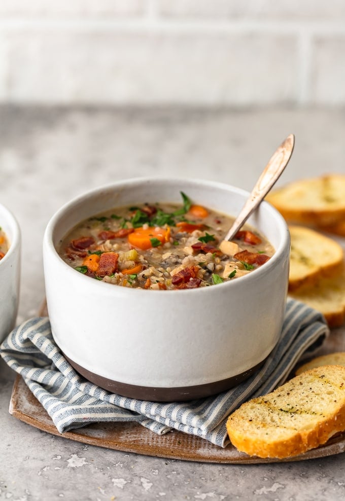 A bowl of creamy chicken and wild rice soup, filled, with chicken, carrots, bacon, mushroom soup, chicken broth, and more