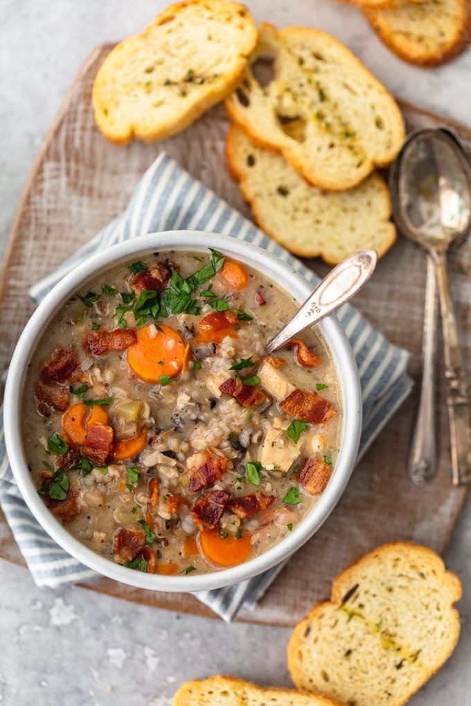 A bowl of homemade chicken and rice soup, with pieces of bread surrounding it