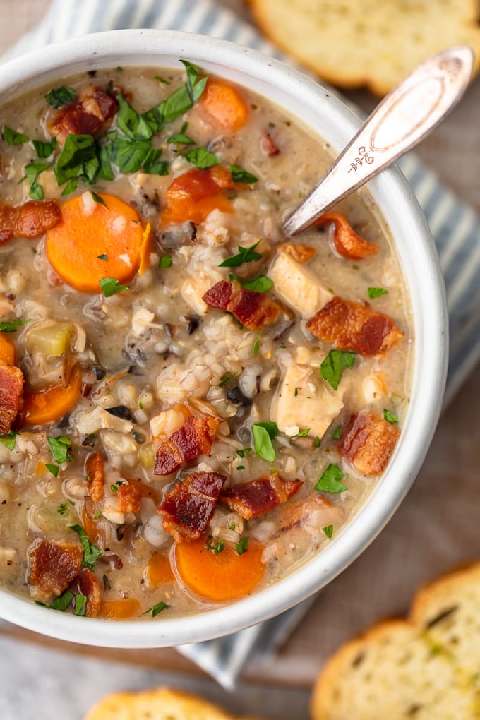 Close up on a bowl of soup with carrots, bacon, rice, chicken, and thyme