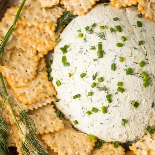 a plate of herb cream cheese with crackers and dill.
