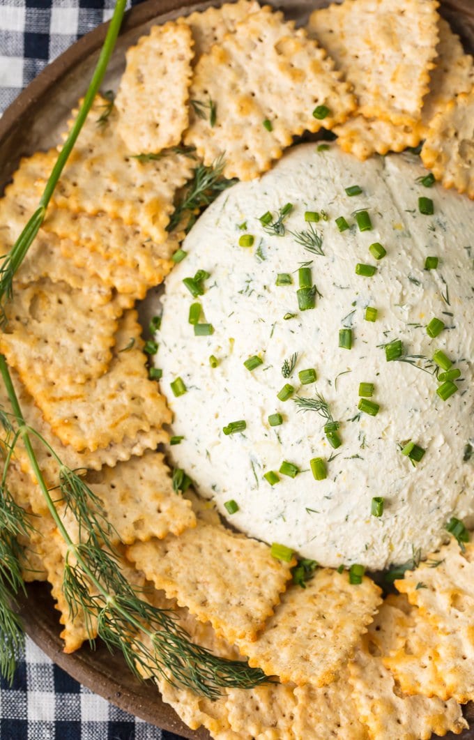 A platter filled with crackers and herb cream cheese dip
