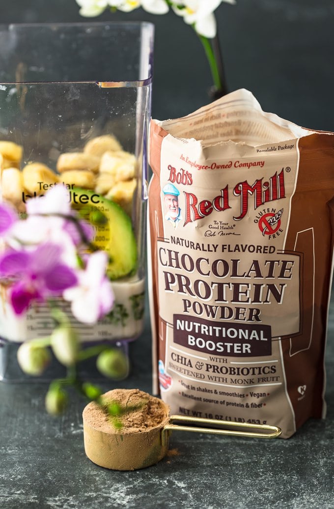 Bob's red mill chocolate protein powder in a bag next to a blender's red mill chocolate protein powder in a bag next to a blender
