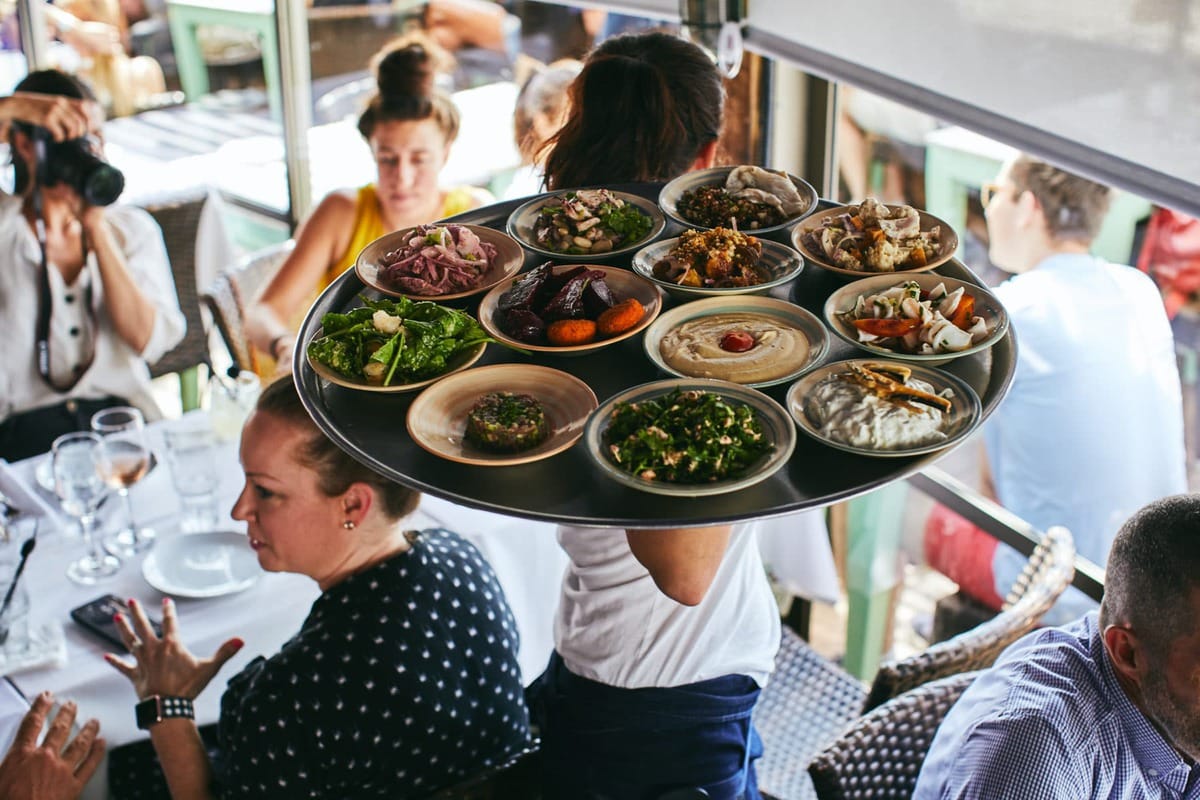 waiter carrying out tray of hummus in Israel