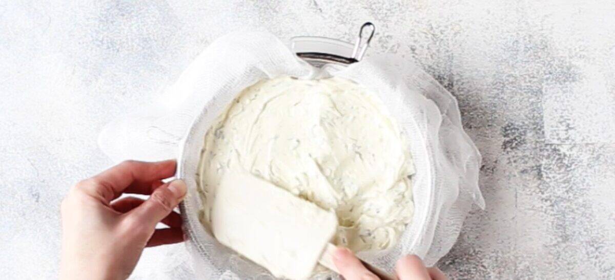 Pouring the cream cheese into a mesh strainer.