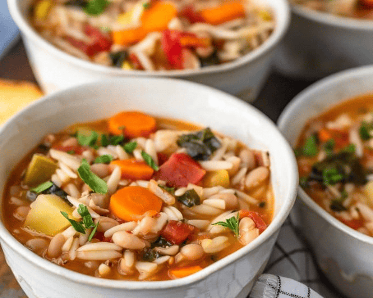 Minestrone soup in 3 white bowls.