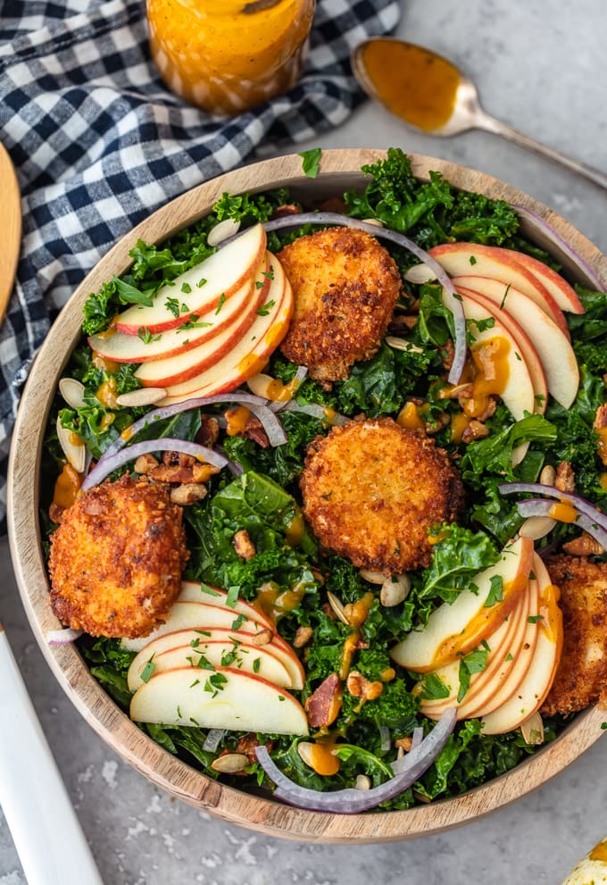 Autumn salad made with kale, apple slices, onions, fried goat cheese, and maple pumpkin salad dressing