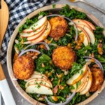 This Autumn Kale Salad recipe is the salad of the season! Made with kale, apples, onions, pumpkin seeds, bacon, fried goat cheese and a maple pumpkin salad dressing, it is the perfect fall salad idea. This delicious kale apple salad makes a tasty and healthy meal you'll want to eat all season long!