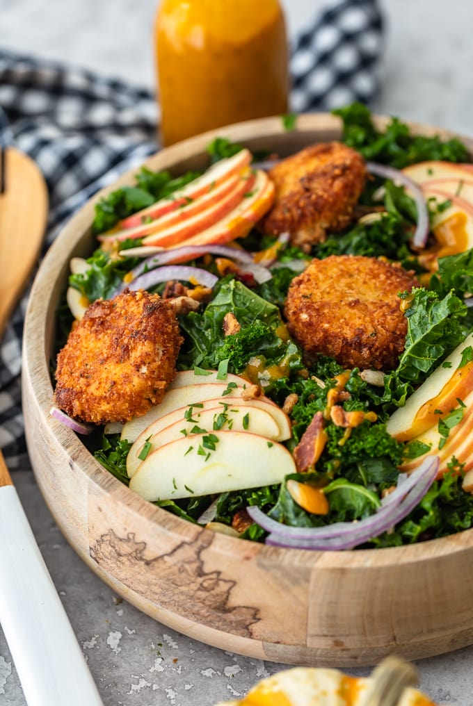 Fall Salad Ideas: Kale salad with onions, apples, goat cheese and more in a wooden bowl