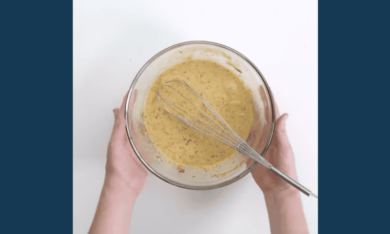 egg custard in a glass bowl with a whisk.