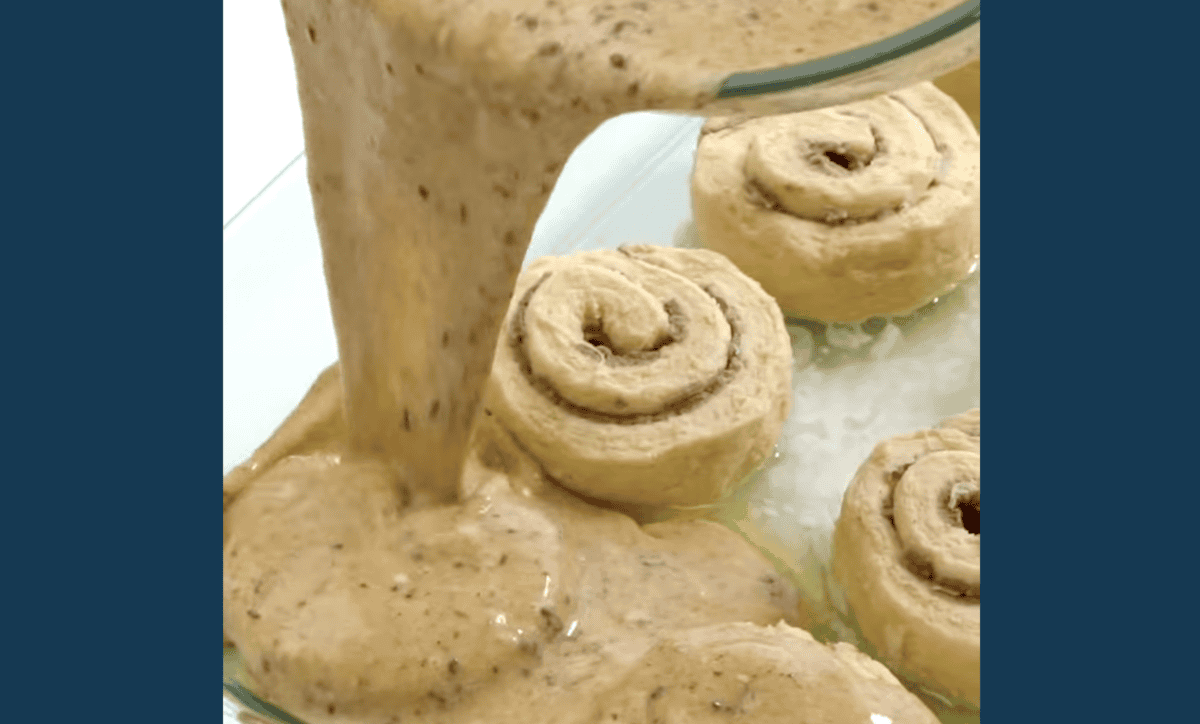 custard poured over cinnamon rolls in a buttered baking dish.