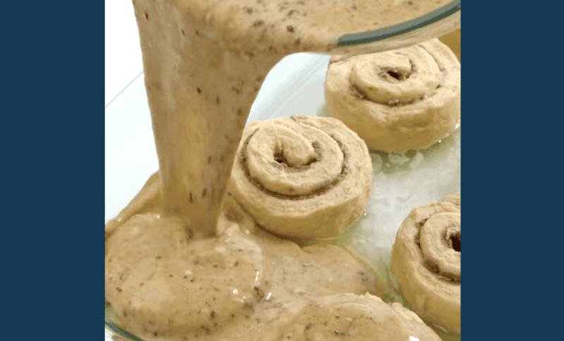 custard poured over cinnamon rolls in a buttered baking dish.