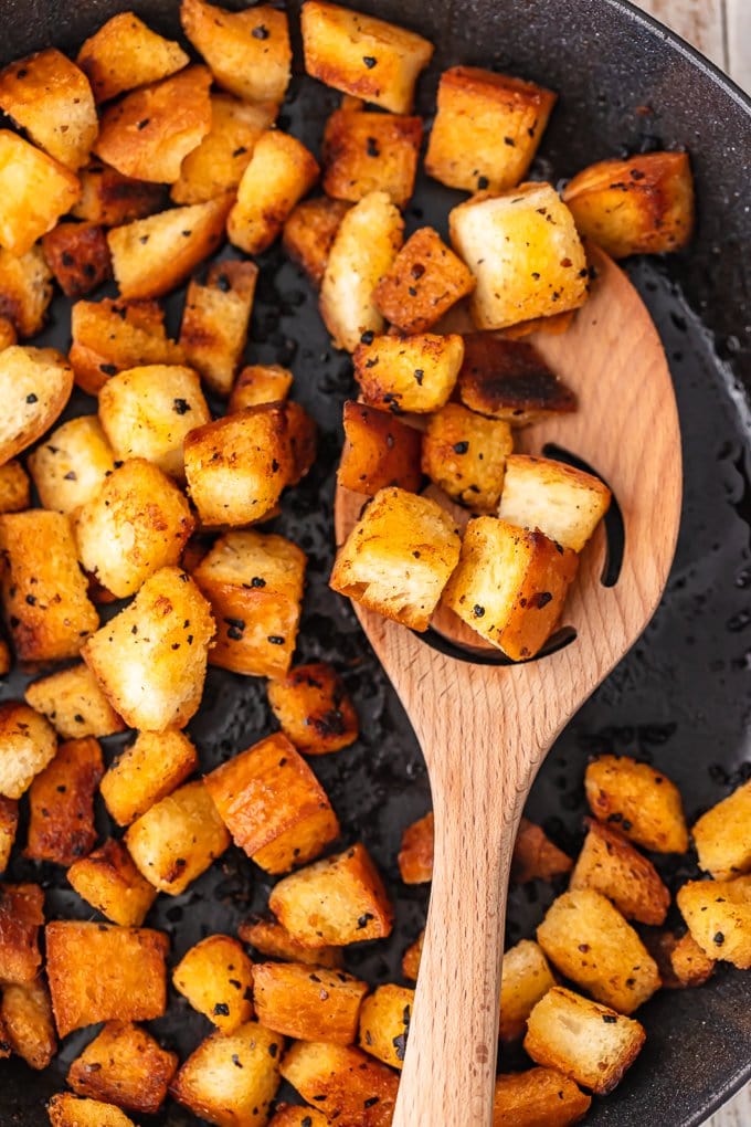 Garlic croutons are so easy to make, and they add the perfect flavor and crunch to your salads. Making croutons on the stove is quick and simple! Just follow this homemade crouton recipe and skip the pre-made ones! garlic croutons frying in a skillet