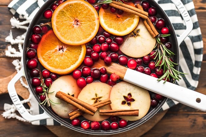 A pot of hot cranberry apple hot cider garnished with orange slices, cloves, and cinnamon sticks