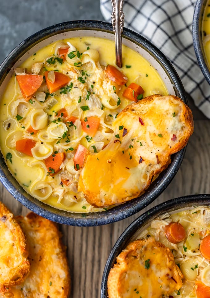 A bowl of chicken mac and cheese soup with a slice of cheesy bread