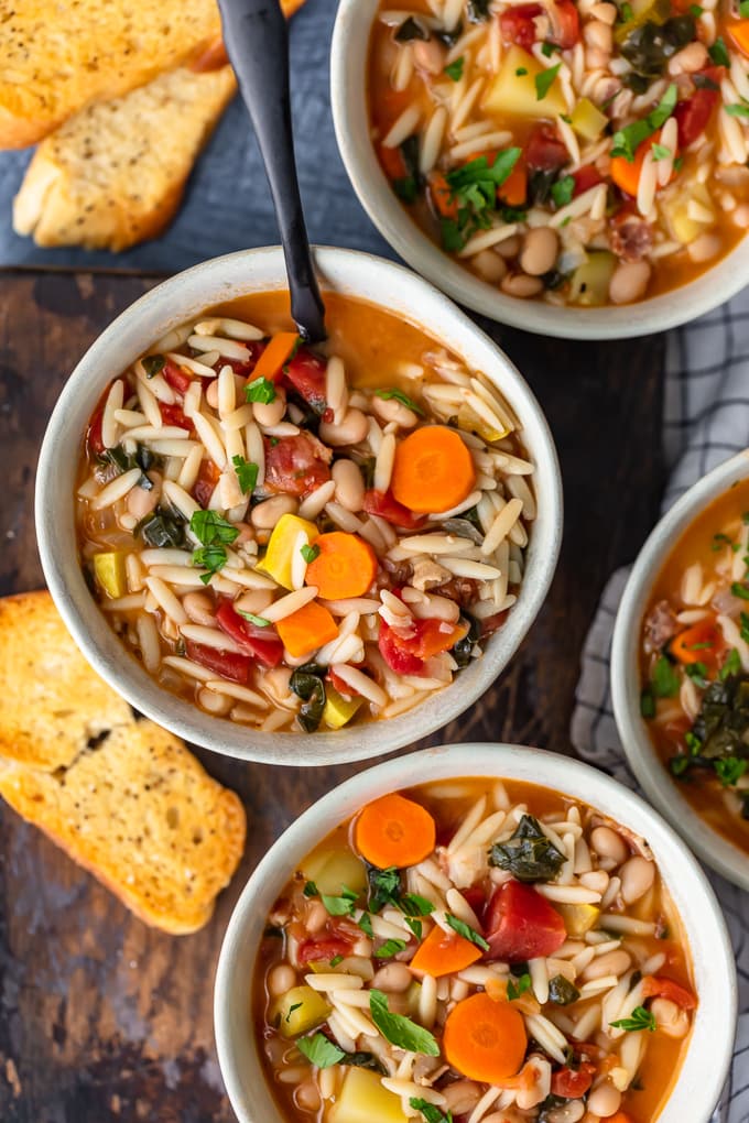 Bowls of minestrone soup with orzo, carrots, squash, and more