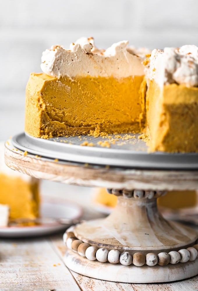 no bake pumpkin cheesecake on a cake stand, with one slice taken out
