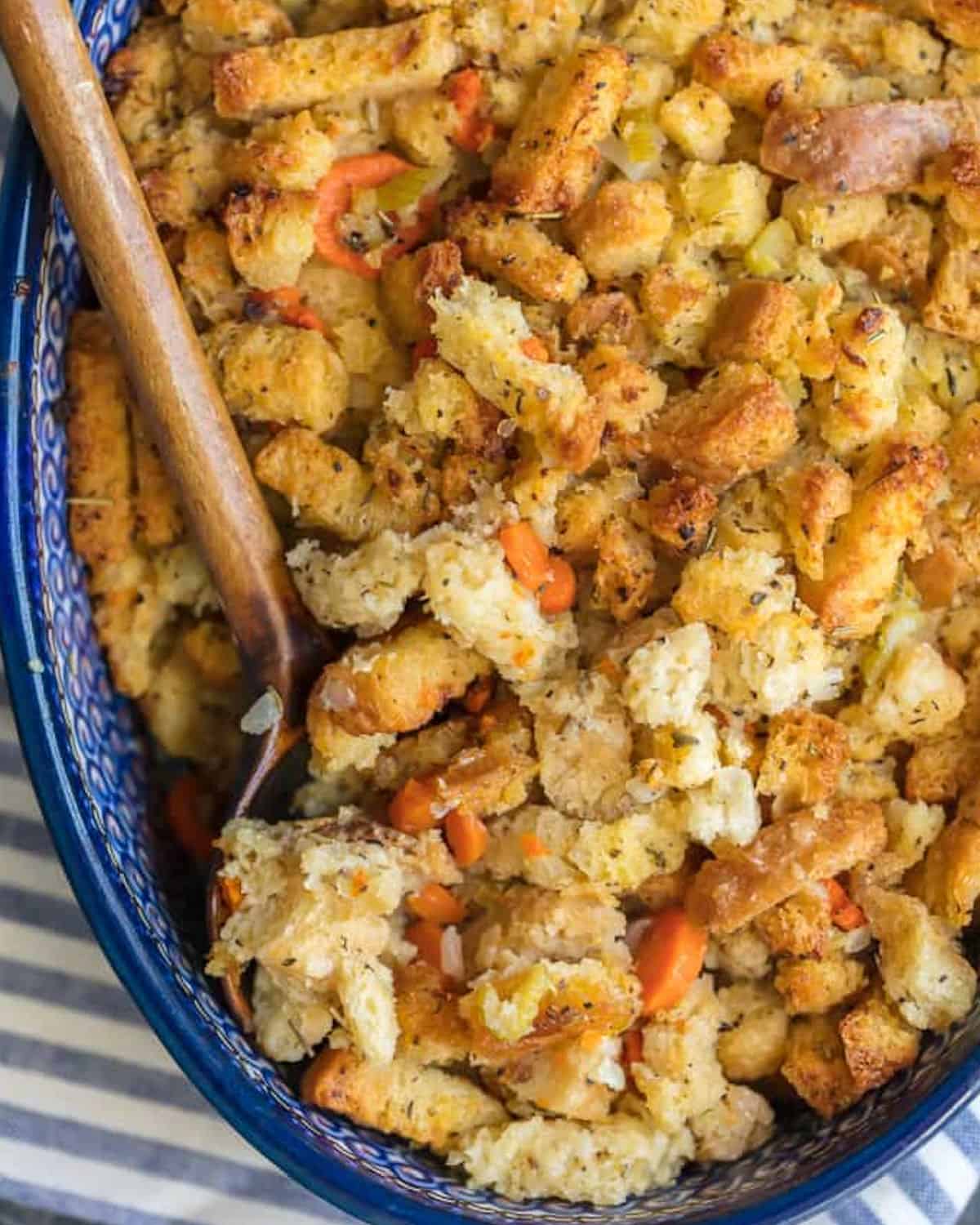 Homemade turkey stuffing in a blue dish with a wooden spoon.