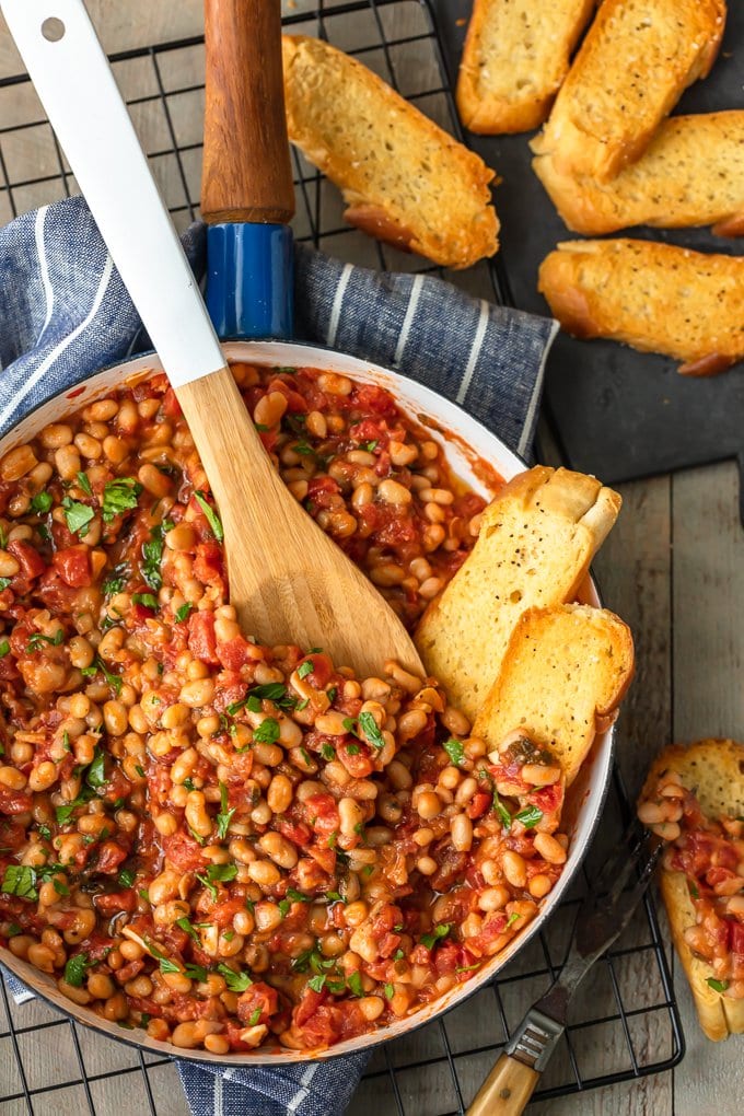 overhead view of a pan filled with tomatoes, white beans, and garlic