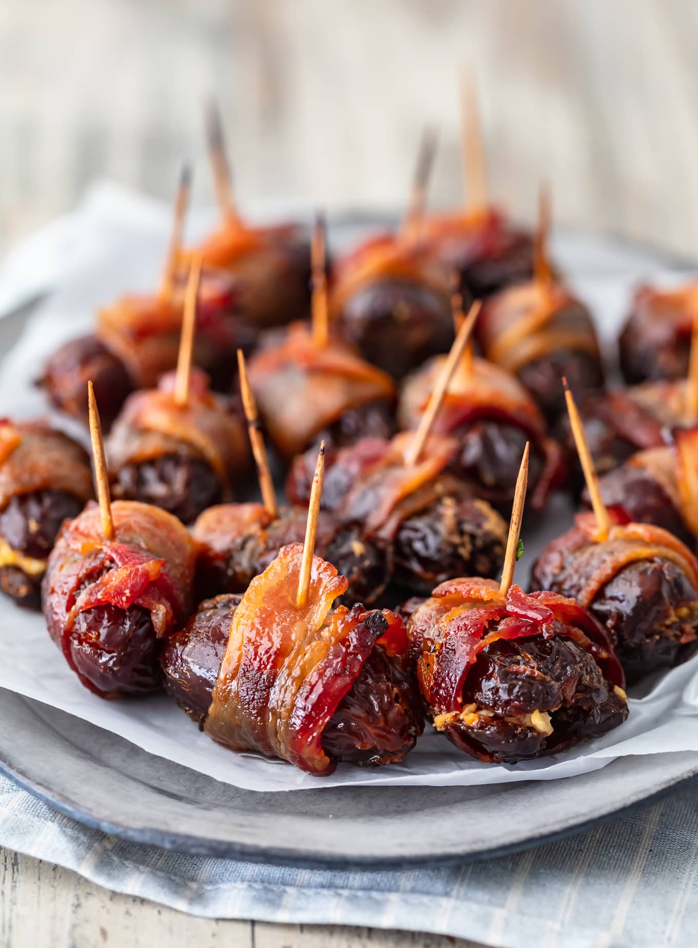 bacon wrapped dates on a serving plate covered with parchment paper