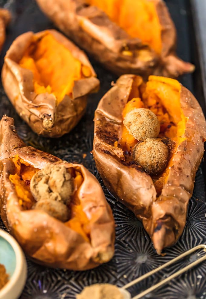 four baked sweet potatoes on a baking tray