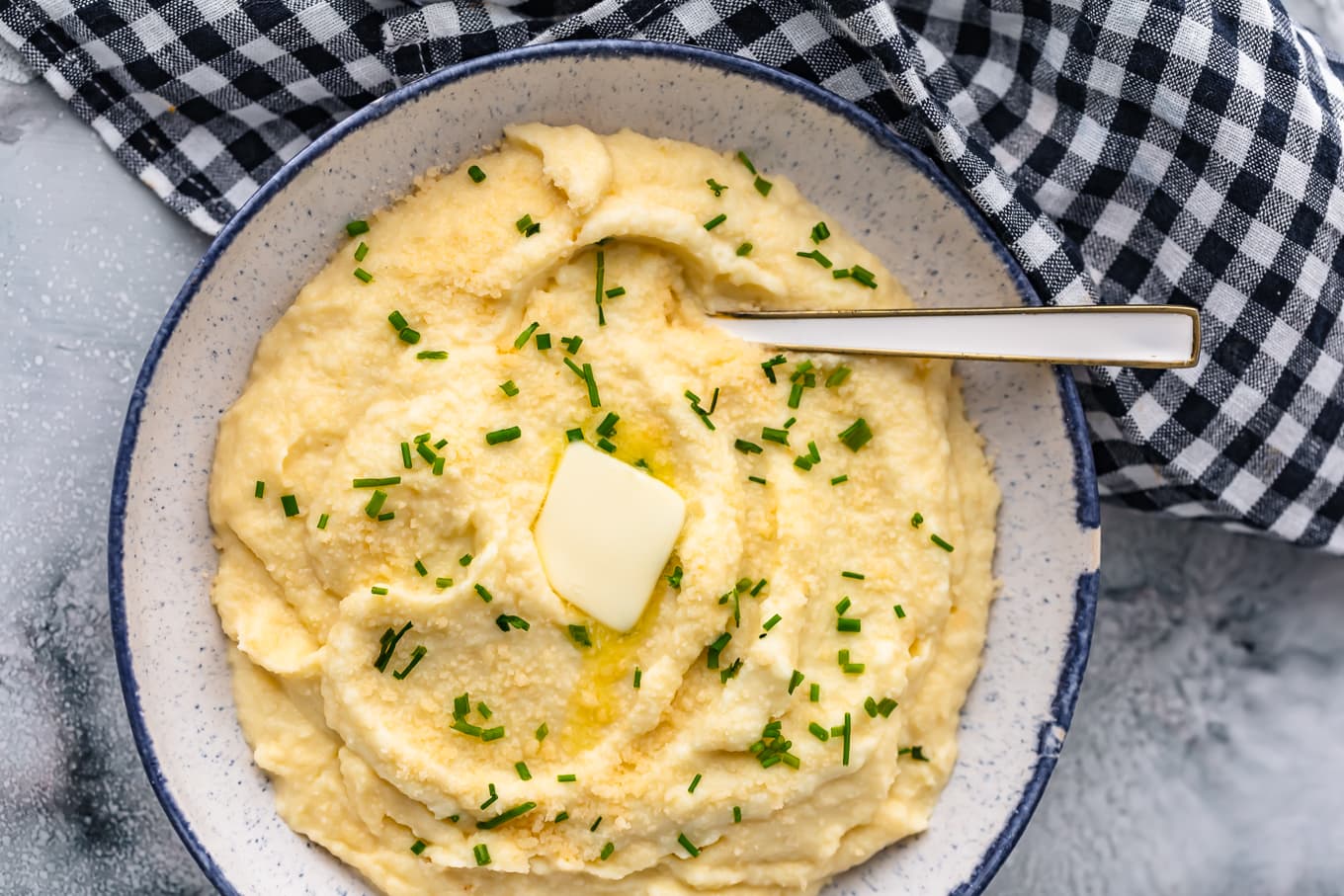 overhead view of a bowl of cauliflower mash next to a checkered dish towel
