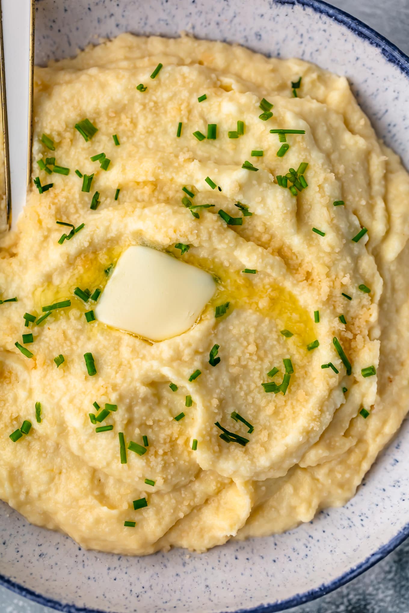 close up view of mashed cauliflower topped with butter and chives