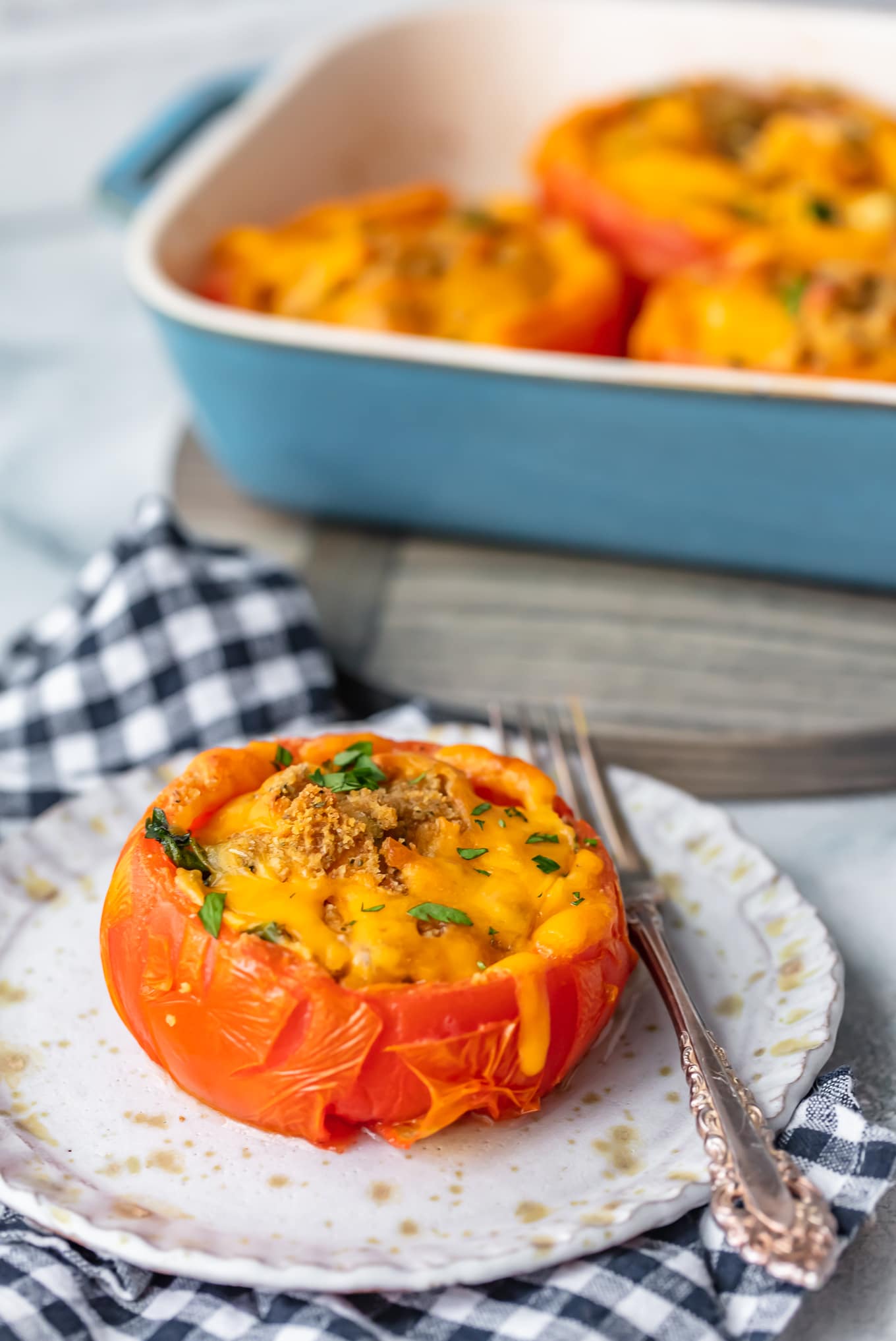 stuffed tomato on plate with fork with baking dish in background