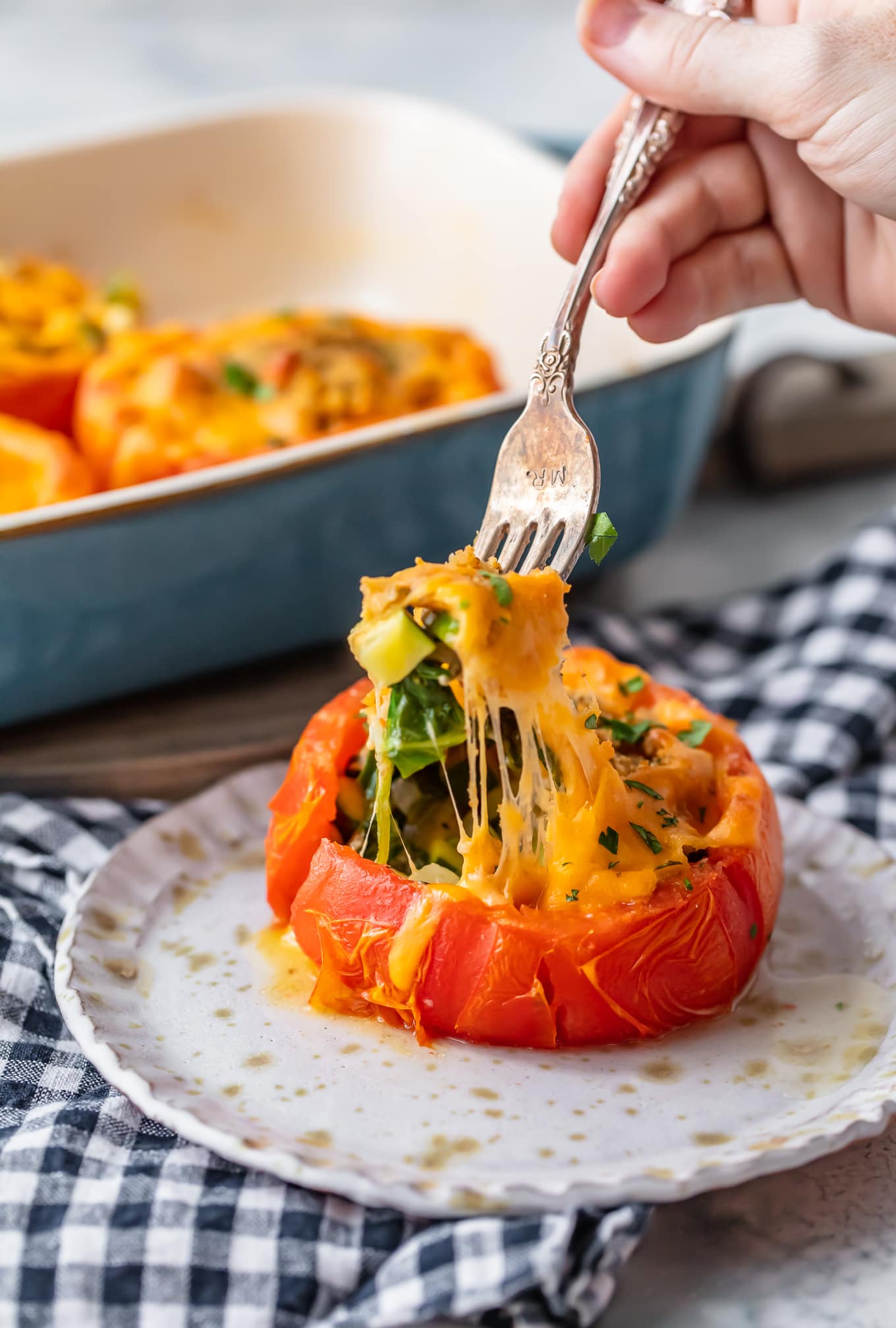shot of stuffed tomato with hand using a fork to pull out stuffing