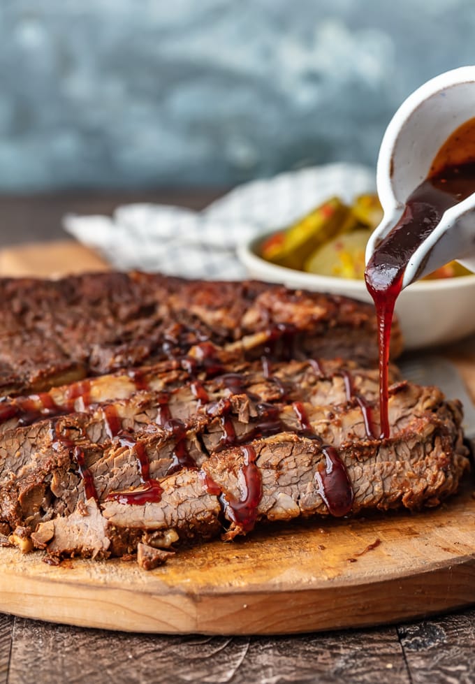 pouring brisket sauce over beef brisket