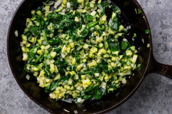zucchini, onion, and spinach in a cast iron pan.