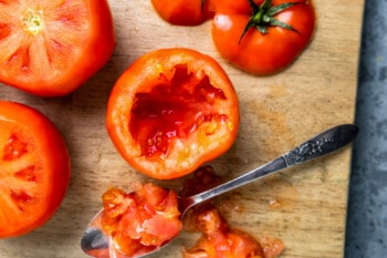 a hollowed out tomato on a cutting board.